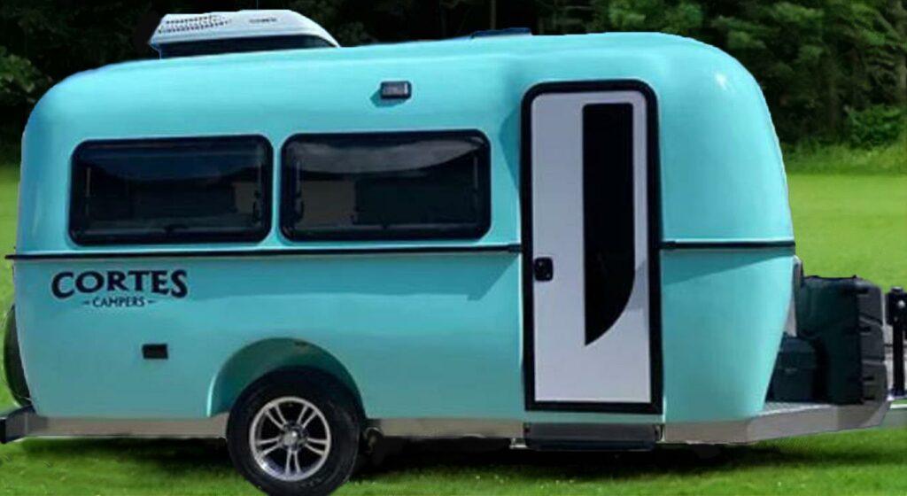 a blue camper trailer parked in a field - 17 ft. Seafoam Green fiberglass hull lightweight camper tr