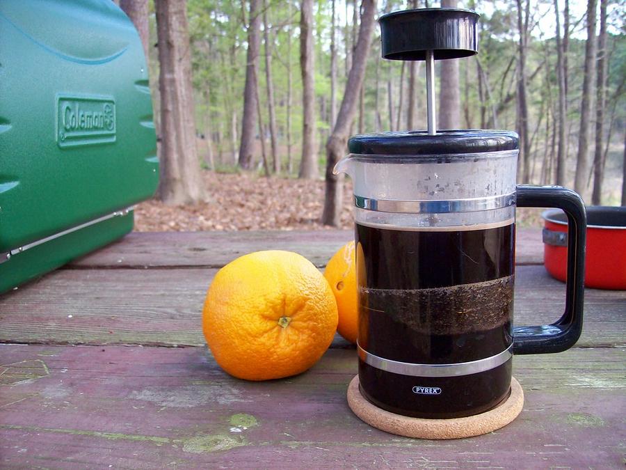 French Press - a coffee pot with a cup of coffee and an orange